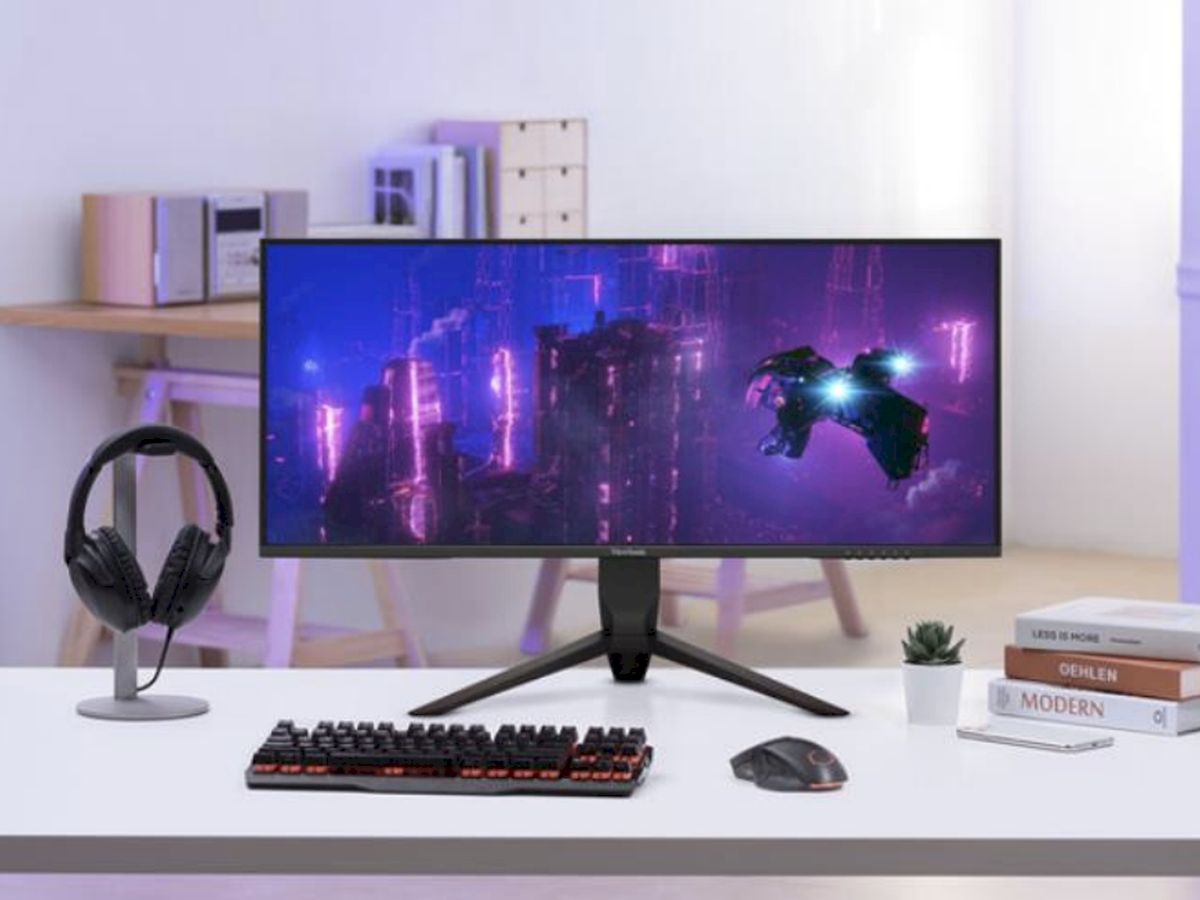 Bureau moderne équipé d’un moniteur ultra-large mettant en scène un univers néon, pour une immersion totale en gaming et en création.