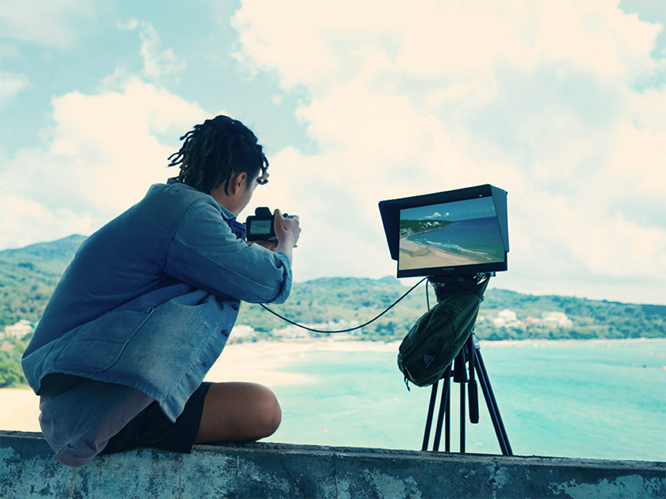 Un creator previzualizează fotografii în aer liber cu un monitor portabil de înaltă rezoluție.